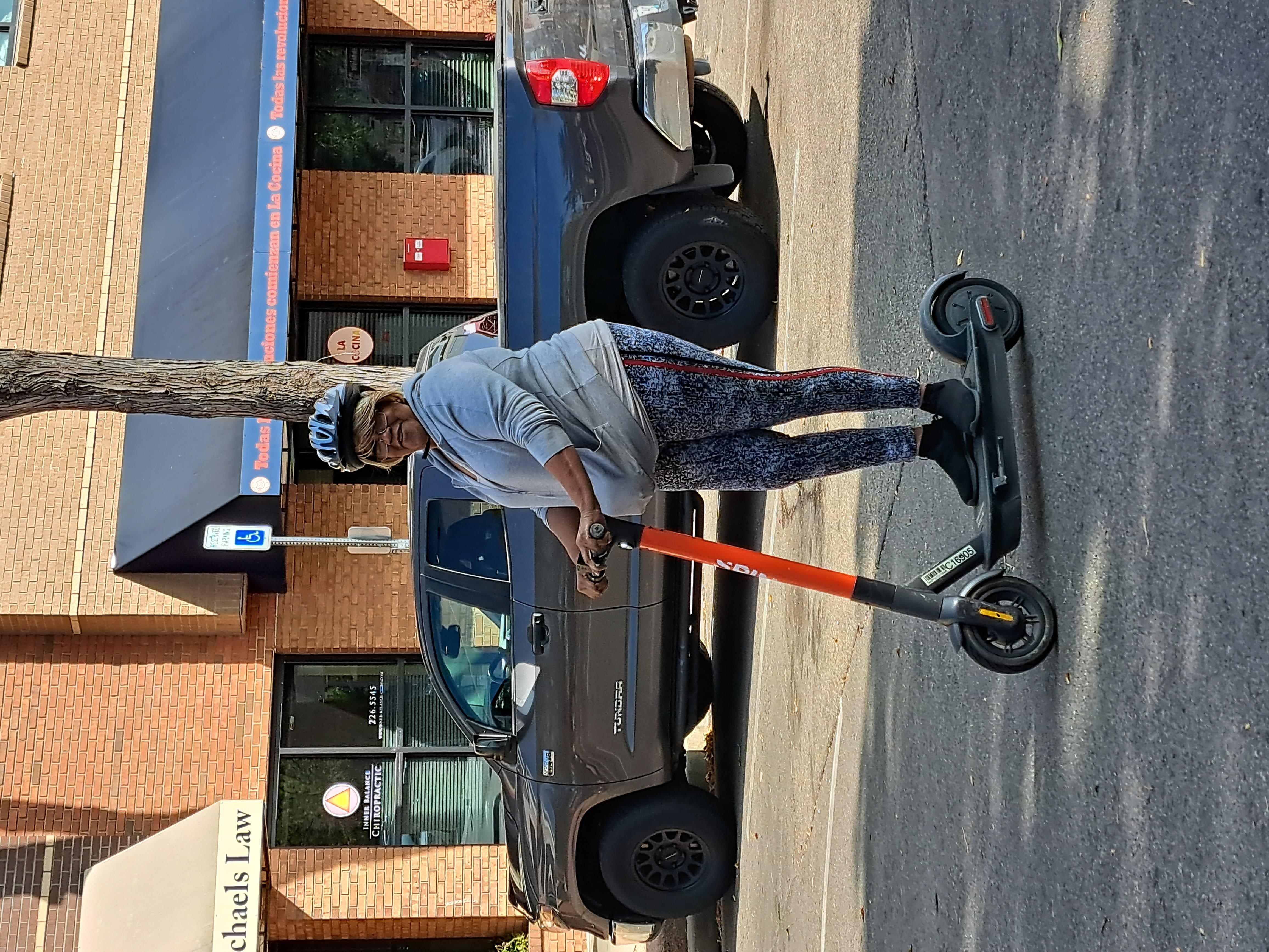 A woman riding an orange Spin scooter