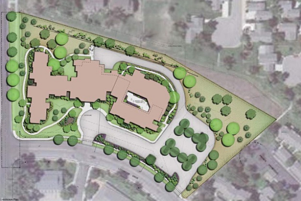 Site plan of a senior living facility. Building fronts on two streets. Ample pathways and trees are shown.