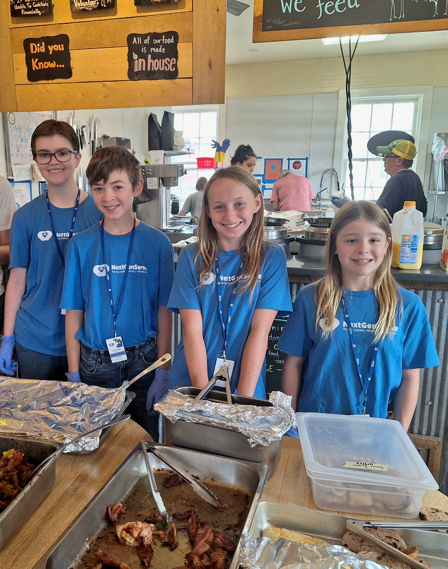 Four kids smiling serving food.